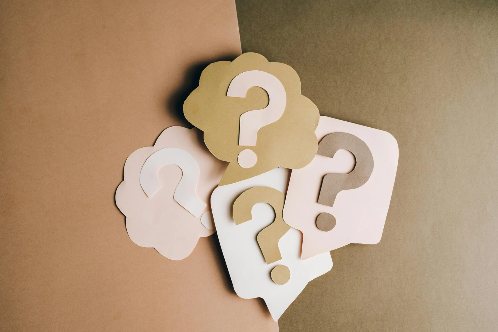 Paper speech bubbles with question marks representing questions and uncertainty.
